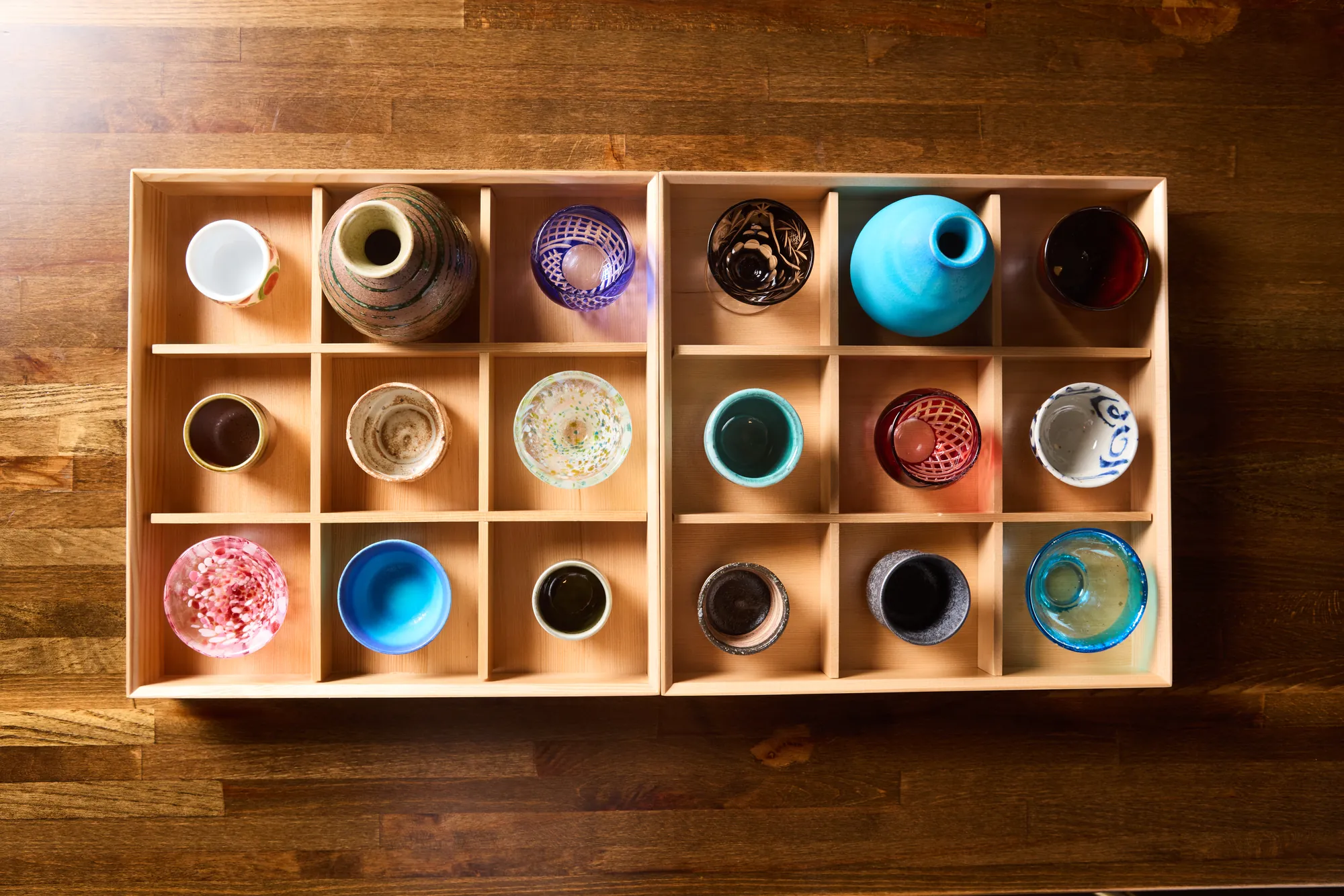 A collection of ochoko sake cups arranged in wooden trays